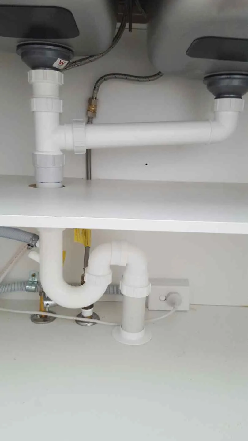 Neat white PVC waste pipework and trap installed under a double kitchen sink